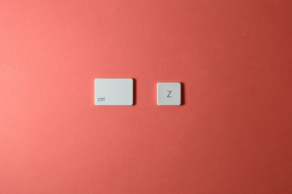 Close-up of 'Ctrl' and 'Z' keyboard keys on a vibrant coral background. Ideal for tech and design themes.