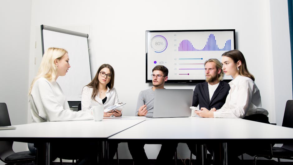 A group of professionals engaged in a business meeting with data presentation.