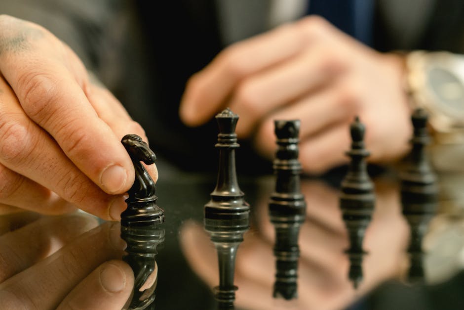 Close-up of a hand moving a chess piece on a reflective board, symbolizing strategy and decision-making.