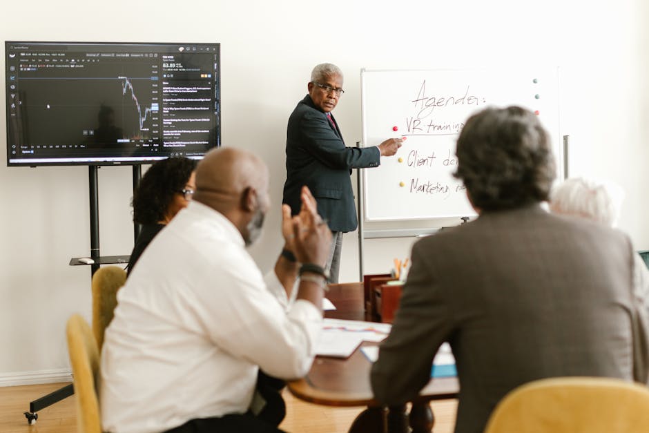 A diverse group of professionals having a meeting in an office setting, discussing on a whiteboard.
