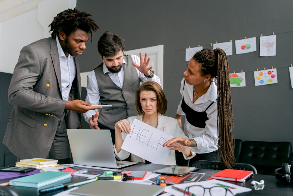 Office scene with diverse colleagues around a stressed woman holding a sign that says 'HELP'. Focus on teamwork dynamics.