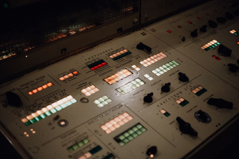 Close-up of an illuminated vintage control panel with various buttons and switches.